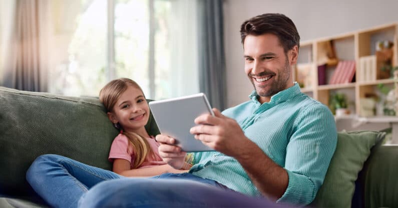 Father using tablet near daughter