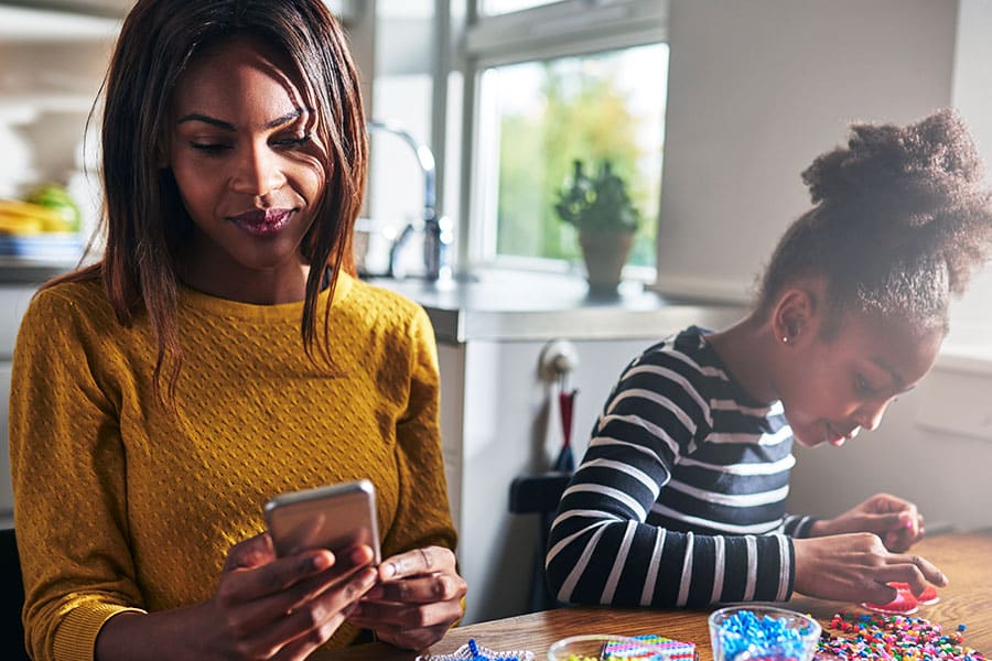 Mother checking phone while minding daughter.